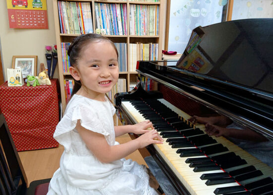 ピアノを弾いて笑う女の子の生徒さんの写真